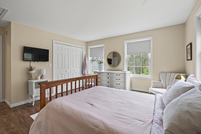 bedroom featuring baseboard heating, baseboards, dark wood-style flooring, and a closet