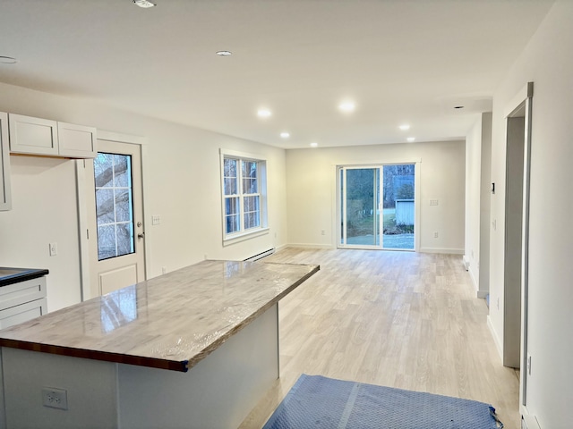 kitchen featuring a baseboard heating unit, white cabinets, light wood finished floors, and a healthy amount of sunlight