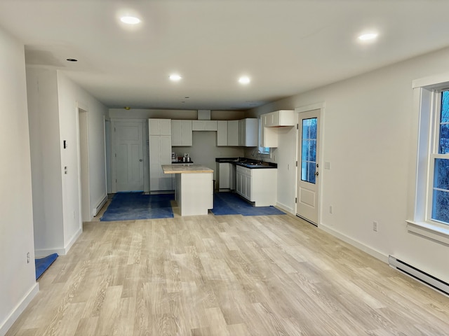 kitchen featuring baseboard heating, a sink, white cabinets, a kitchen island, and recessed lighting