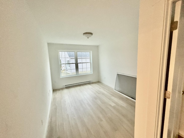 empty room with wood finished floors and baseboard heating