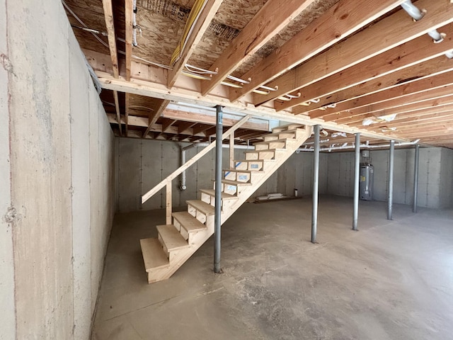 unfinished basement featuring stairs and gas water heater