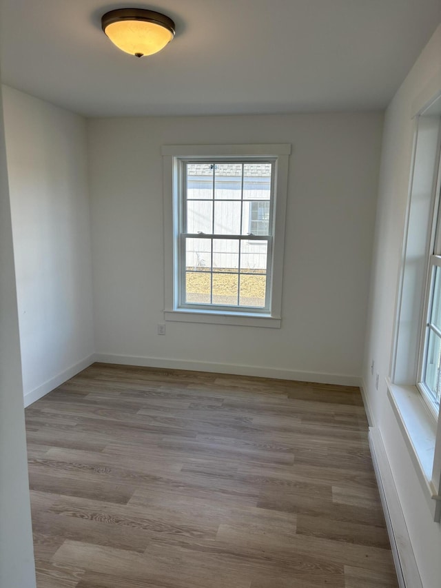 spare room with baseboards and wood finished floors