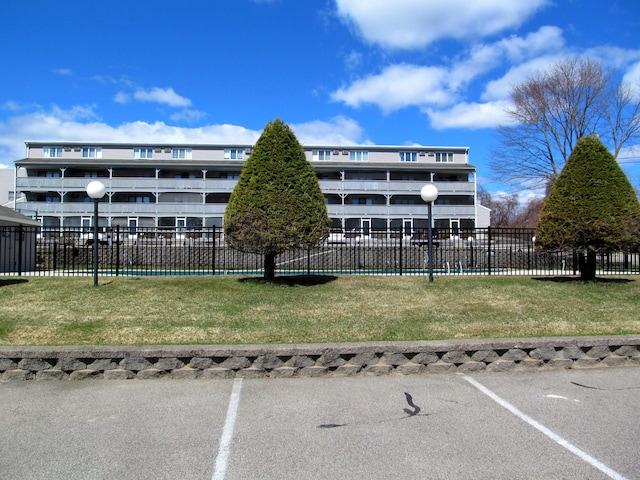 view of building exterior with fence and uncovered parking