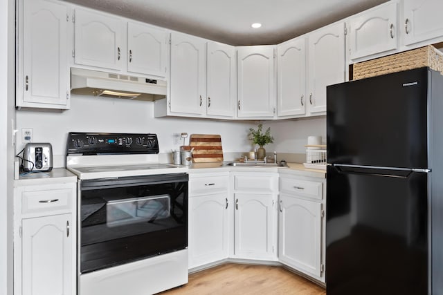 kitchen featuring light countertops, white cabinets, under cabinet range hood, white electric stove, and freestanding refrigerator