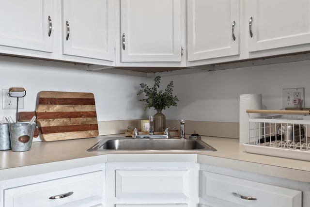 kitchen featuring white cabinetry, a sink, and light countertops