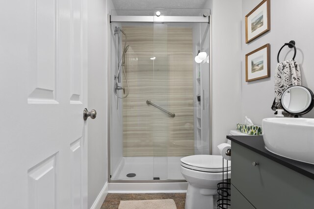 bathroom with toilet, baseboards, vanity, and a stall shower