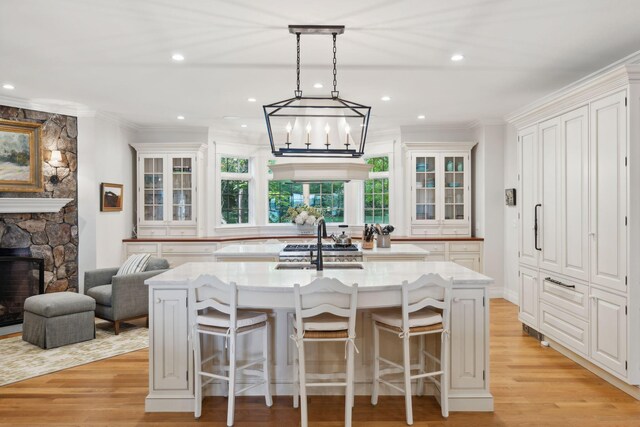 184 Spruce Point Rd, Yarmouth, ME 04096 - kitchen featuring an inviting chandelier, an island with sink, light wood-style floors, and glass insert cabinets