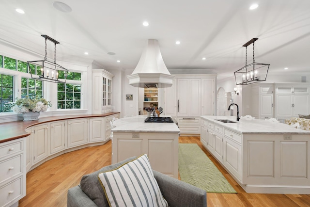184 Spruce Point Rd, Yarmouth, ME 04096 - kitchen with a notable chandelier, stainless steel gas cooktop, an island with sink, and white cabinetry