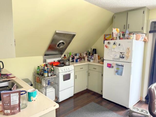kitchen with lofted ceiling, white appliances, light countertops, and dark wood finished floors
