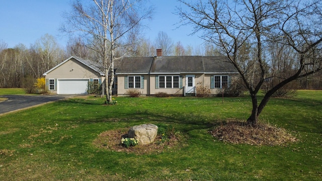 view of front of property featuring an attached garage, driveway, a chimney, and a front lawn