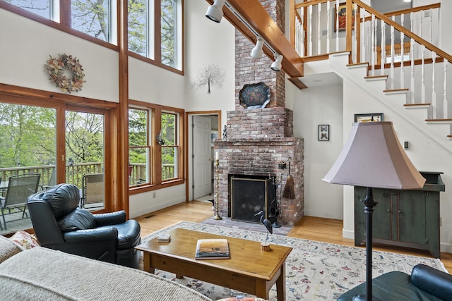 175 Quail Run Rd, Bristol, ME 04539 - living room featuring a high ceiling, a fireplace, wood finished floors, stairway, and baseboards