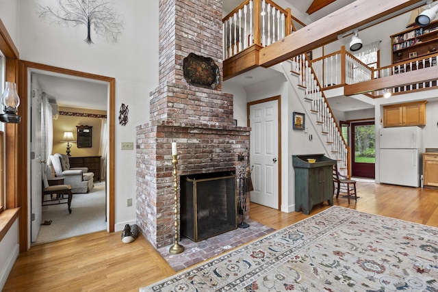175 Quail Run Rd, Bristol, ME 04539 - living area featuring light wood-style floors, a high ceiling, a fireplace, and stairs