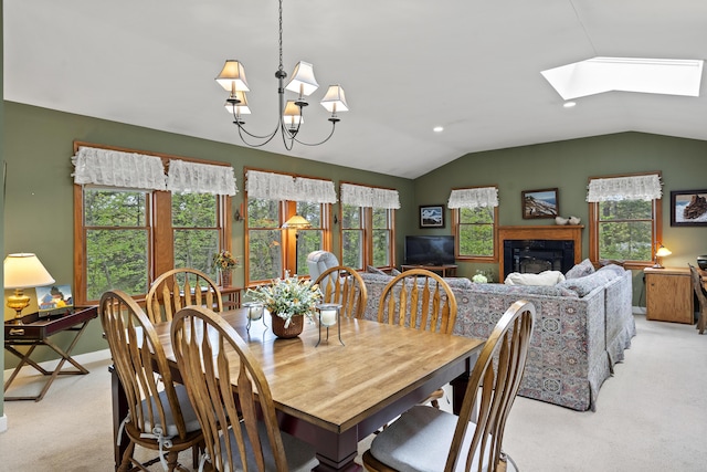 175 Quail Run Rd, Bristol, ME 04539 - dining area with light colored carpet, a skylight, vaulted ceiling, a glass covered fireplace, and a chandelier