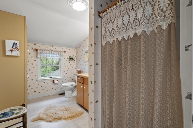 175 Quail Run Rd, Bristol, ME 04539 - full bath with lofted ceiling, toilet, vanity, wallpapered walls, and wood finished floors
