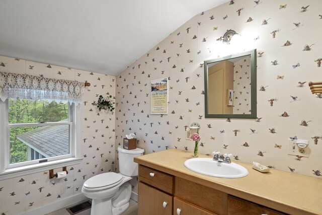 175 Quail Run Rd, Bristol, ME 04539 - bathroom with vaulted ceiling, wallpapered walls, toilet, vanity, and baseboards