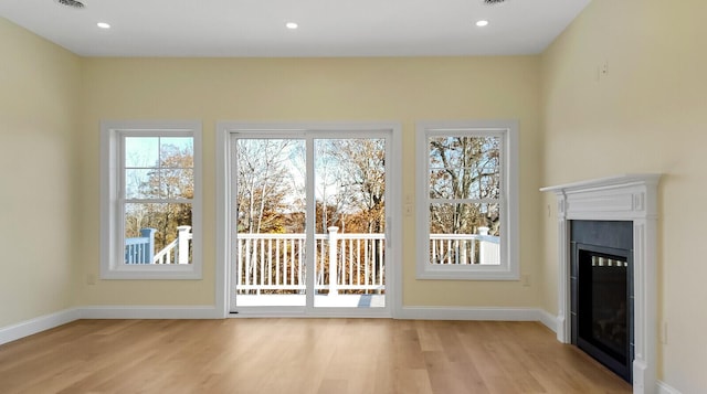 LOT16 Beech St Unit 16, Hallowell, ME 04347 - unfurnished living room featuring baseboards, a healthy amount of sunlight, a glass covered fireplace, and light wood-style floors