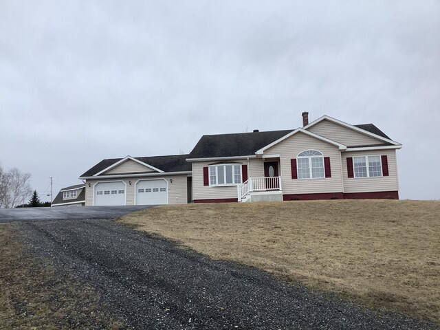 view of front of property with a chimney, an attached garage, driveway, and a front lawn