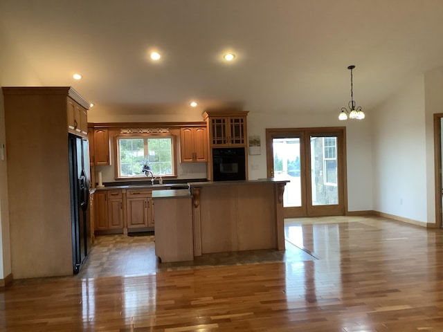 kitchen featuring dark countertops, light wood-style flooring, a kitchen island, and black appliances