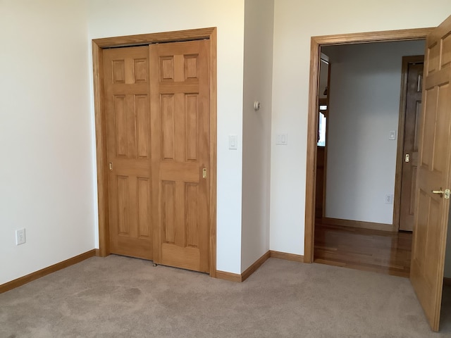 interior space featuring baseboards, a closet, and light colored carpet