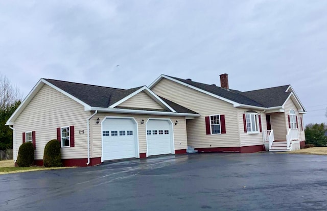 view of front of property featuring a chimney, an attached garage, aphalt driveway, and roof with shingles
