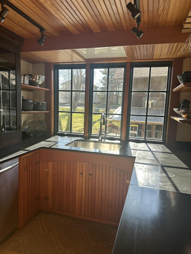 kitchen featuring beam ceiling, a sink, wood ceiling, brown cabinetry, and dishwasher