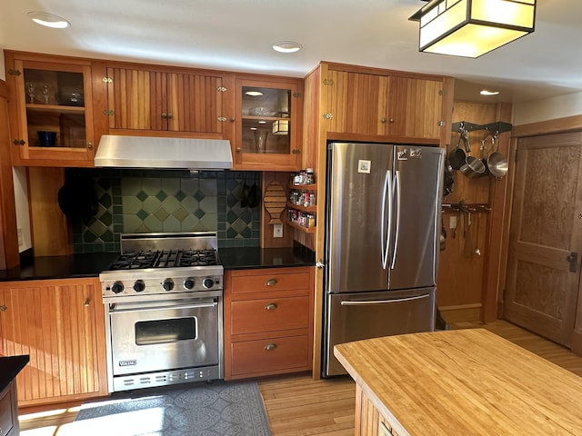 kitchen with stainless steel appliances, brown cabinets, light wood-style floors, and range hood