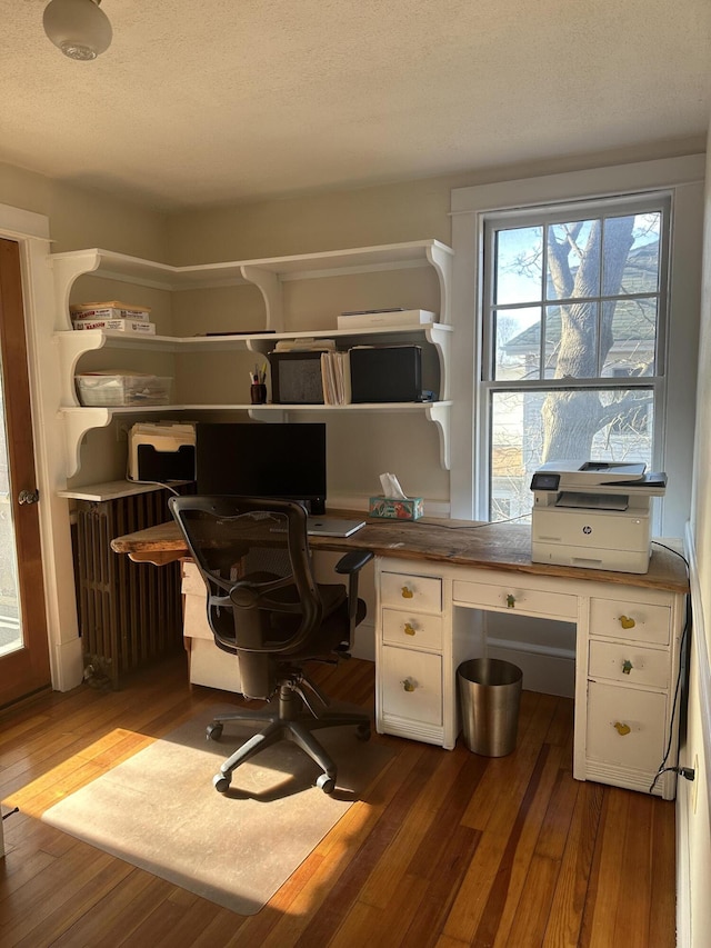 office space featuring built in study area, radiator, wood finished floors, and a textured ceiling