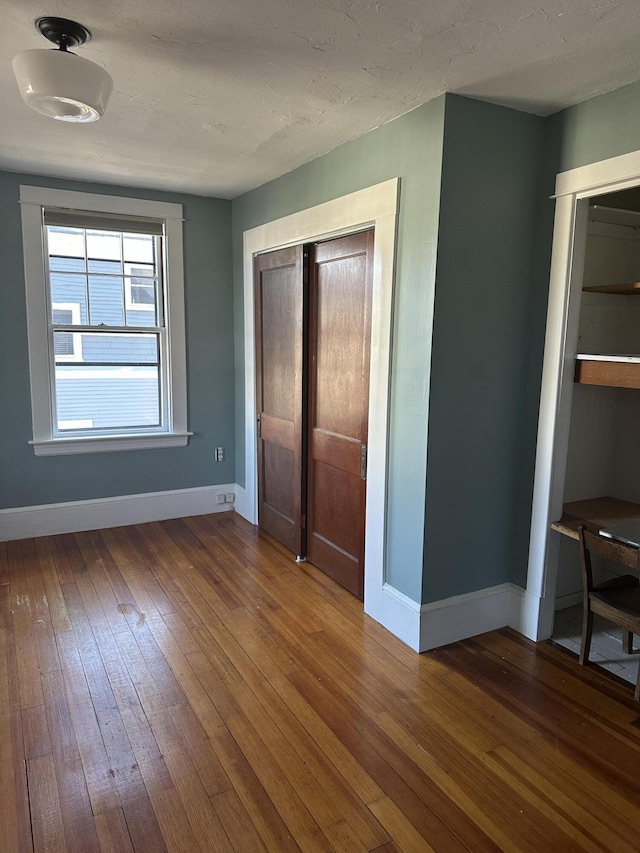 unfurnished bedroom featuring baseboards and hardwood / wood-style flooring