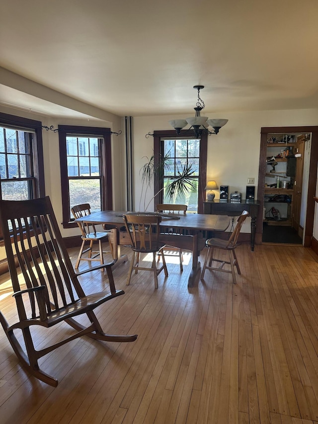 dining area with hardwood / wood-style floors, plenty of natural light, and an inviting chandelier