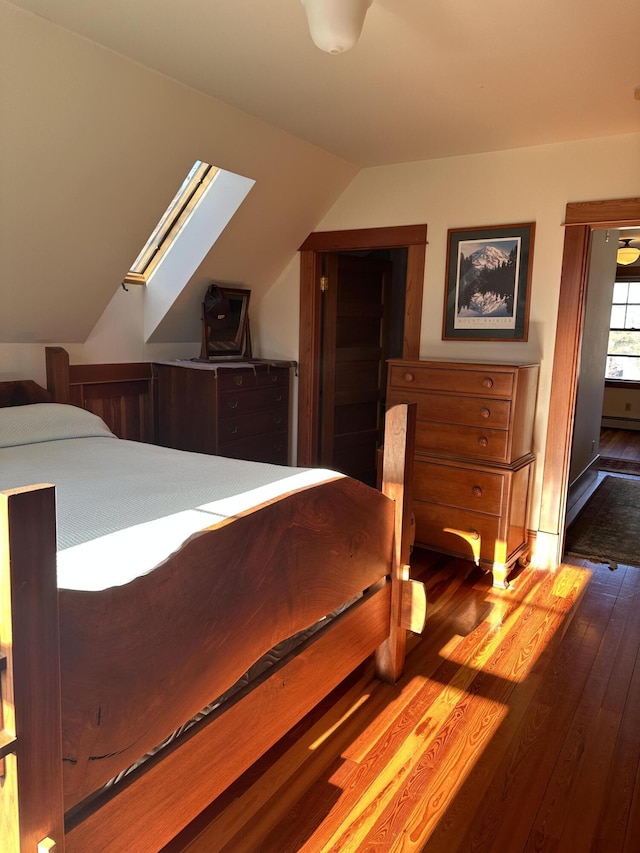 bedroom with vaulted ceiling with skylight and hardwood / wood-style flooring