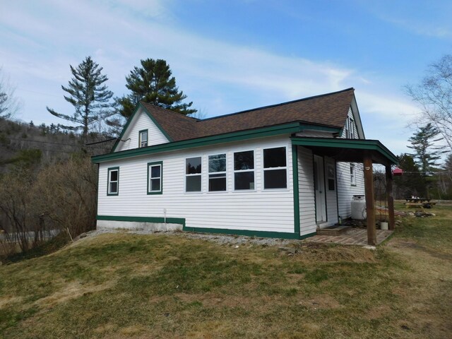 view of property exterior featuring a yard and a shingled roof