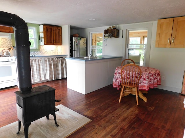 346 Bear River Rd, Newry, ME 04261 - kitchen with freestanding refrigerator, white range with gas cooktop, a wood stove, dark wood-type flooring, and tasteful backsplash