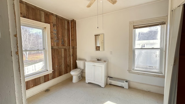 11 Maple St, Milo, ME 04463 - bathroom with baseboard heating, healthy amount of natural light, baseboards, toilet, and wood walls