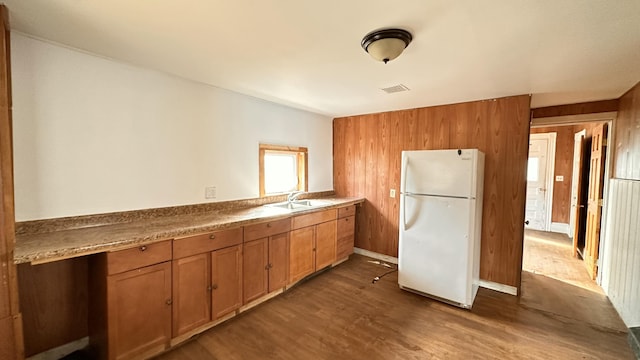 11 Maple St, Milo, ME 04463 - kitchen featuring freestanding refrigerator, dark wood-type flooring, a sink, wooden walls, and brown cabinetry