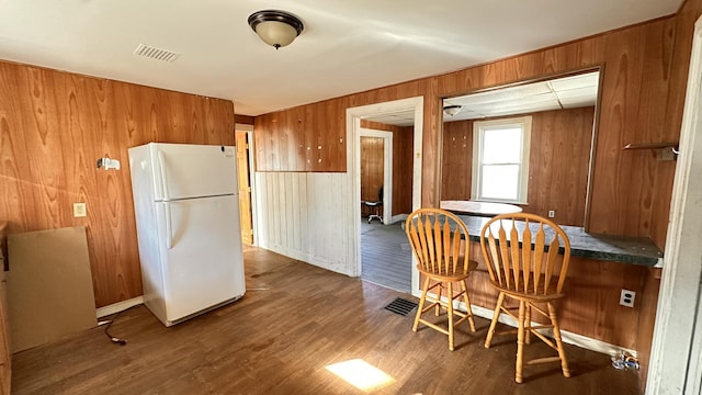 11 Maple St, Milo, ME 04463 - kitchen featuring freestanding refrigerator, wooden walls, brown cabinets, wood finished floors, and dark countertops