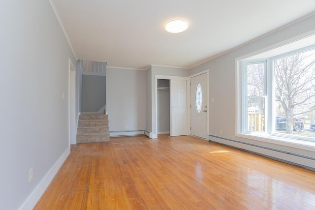 foyer entrance with a baseboard heating unit, ornamental molding, stairs, and light wood-type flooring