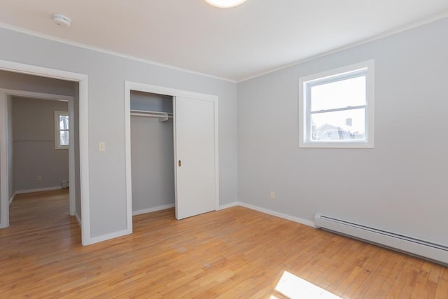 unfurnished bedroom featuring a baseboard heating unit, light wood finished floors, baseboards, and ornamental molding