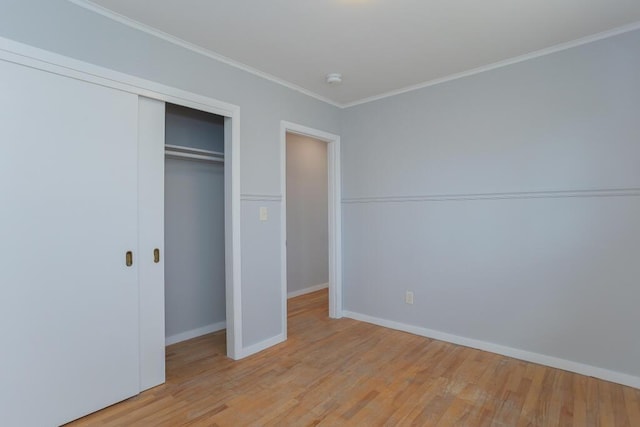 unfurnished bedroom with light wood-type flooring, a closet, crown molding, and baseboards