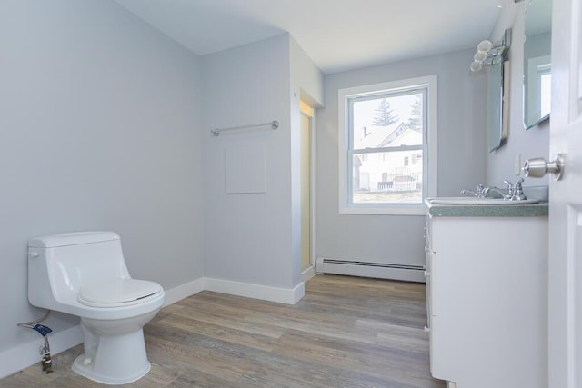 bathroom with a stall shower, toilet, baseboards, baseboard heating, and wood finished floors