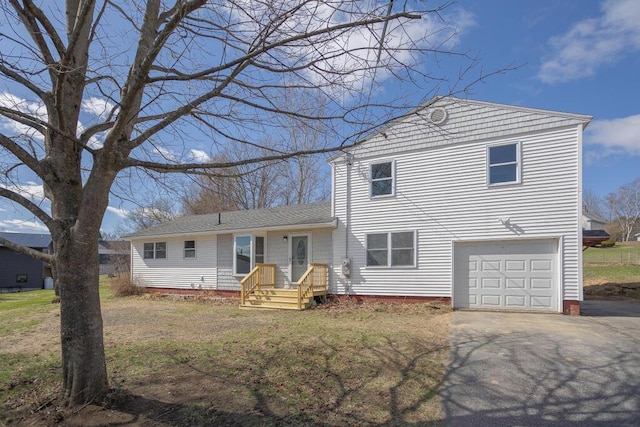 tri-level home featuring an attached garage, a front lawn, aphalt driveway, and roof with shingles