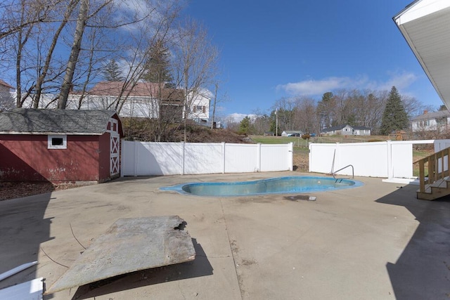 view of pool featuring a storage shed, a patio area, an outbuilding, and a fenced backyard