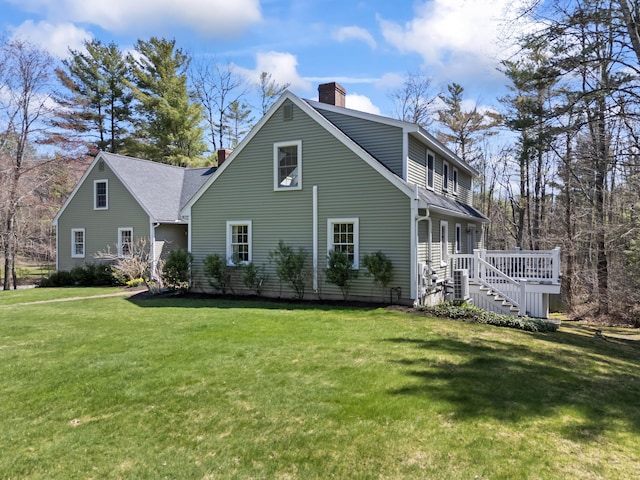 exterior space with a lawn, a chimney, stairs, and a wooden deck