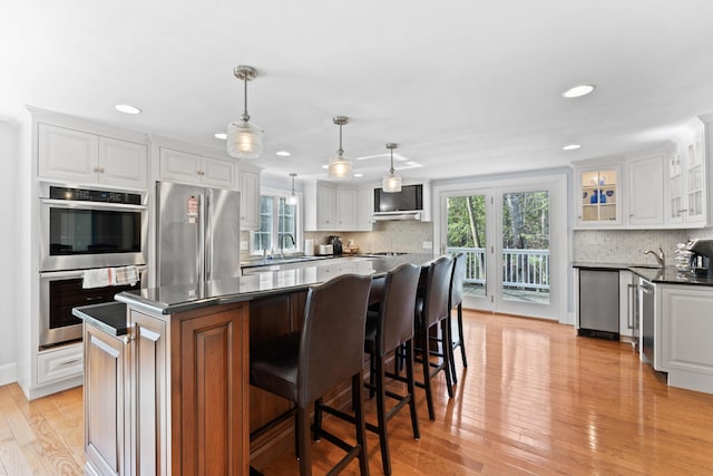 kitchen with a wealth of natural light, dark countertops, stainless steel appliances, and a sink