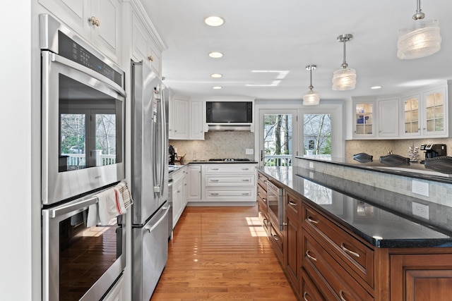 kitchen featuring white cabinets, light wood-type flooring, appliances with stainless steel finishes, and decorative backsplash