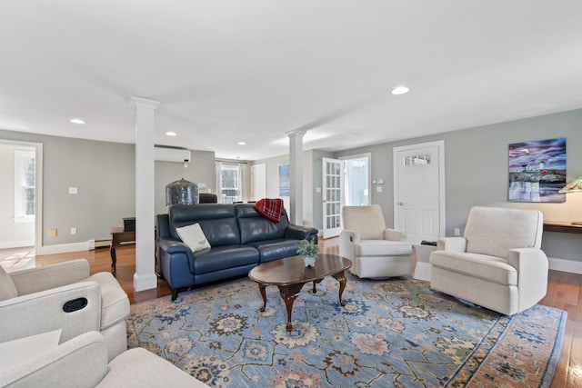 living area featuring recessed lighting, wood finished floors, an AC wall unit, and ornate columns