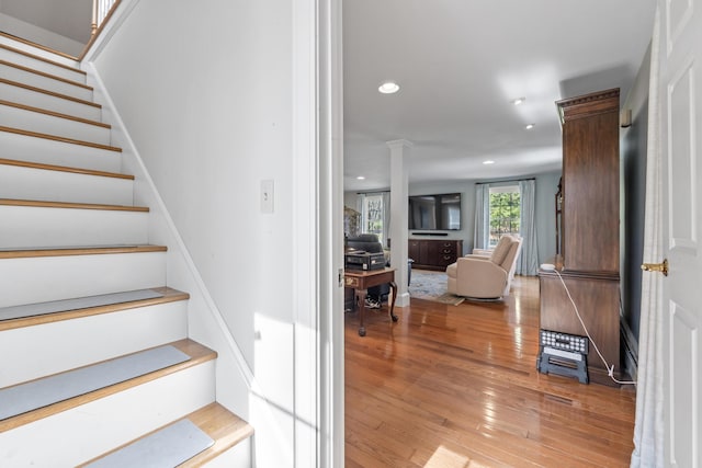 stairway featuring hardwood / wood-style floors, decorative columns, and recessed lighting