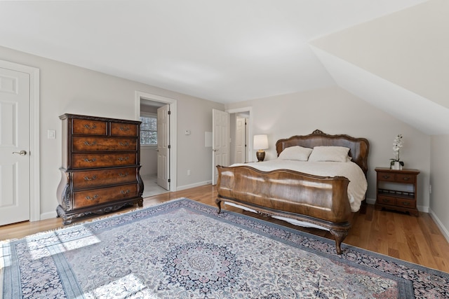 bedroom featuring lofted ceiling, light wood-style floors, and baseboards