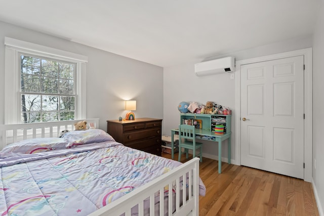 bedroom with a wall mounted AC and light wood-type flooring