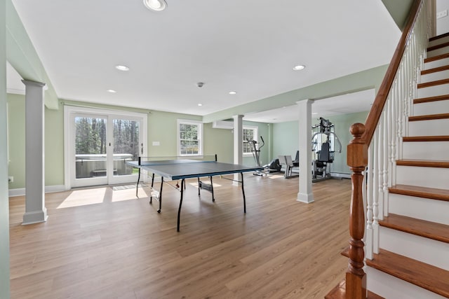 game room with light wood-type flooring, plenty of natural light, and decorative columns