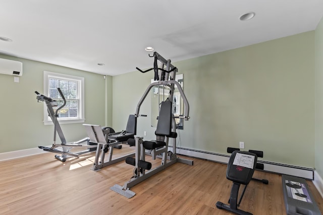 workout area featuring a baseboard heating unit, an AC wall unit, light wood-type flooring, baseboards, and recessed lighting